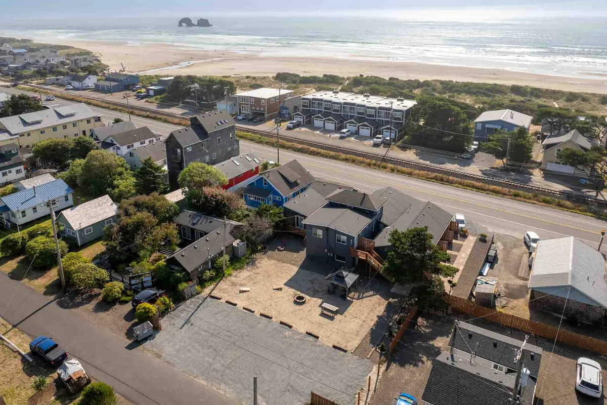 A vibrant beachfront scene featuring a sandy shoreline, scenic coastline, and colorful houses in the background. The image captures a casual, inviting atmosphere perfect for family gatherings, beach walks, or outdoor barbecues.