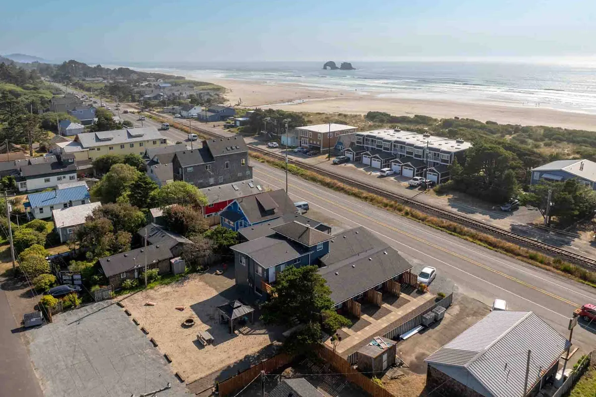 A picturesque view of the beach with ocean waves, iconic rock formations, and nearby neighborhood houses. The scene highlights the beauty of coastal walks, the allure of exploring tide pools, and the inviting landscape for both sunrise and sunset strolls.