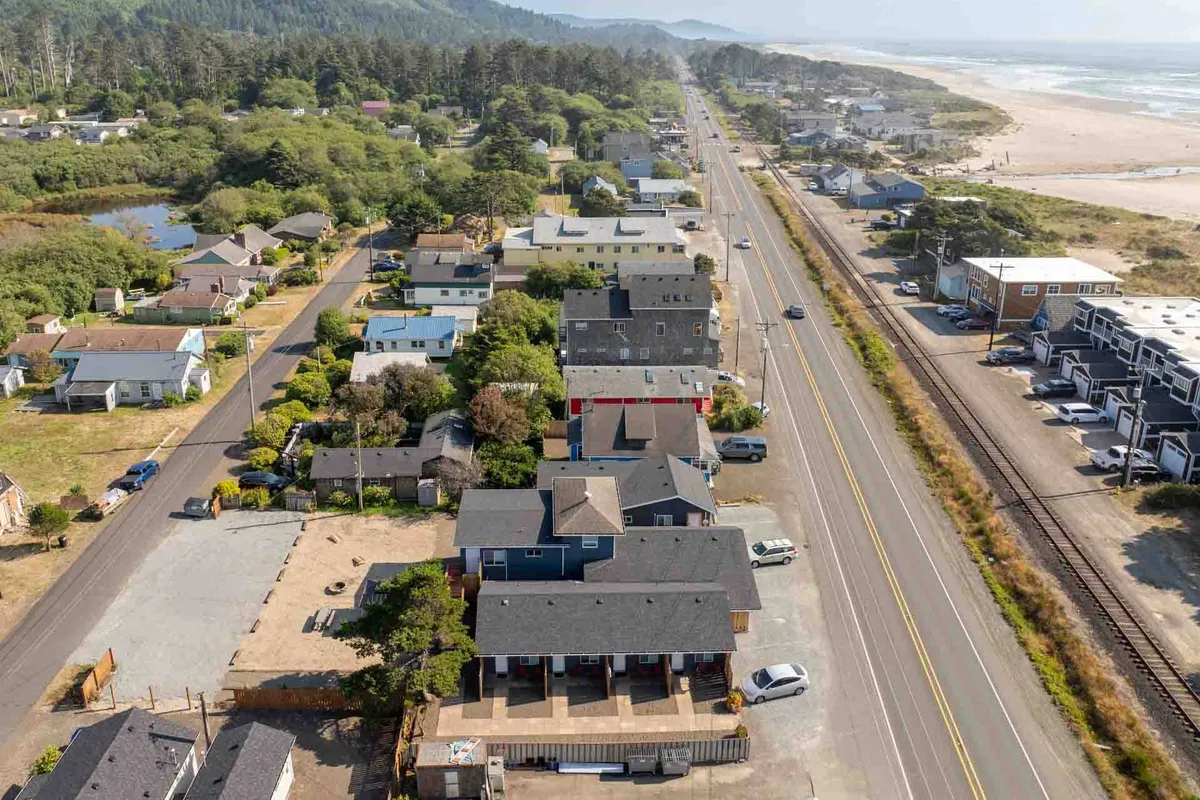 A sweeping coastal view showing the neighborhood layout with a roadway leading directly to the beach. The image includes the community setting, nearby beach access, and the inviting ocean horizon, highlighting both the local atmosphere and the adventure awaiting outside.