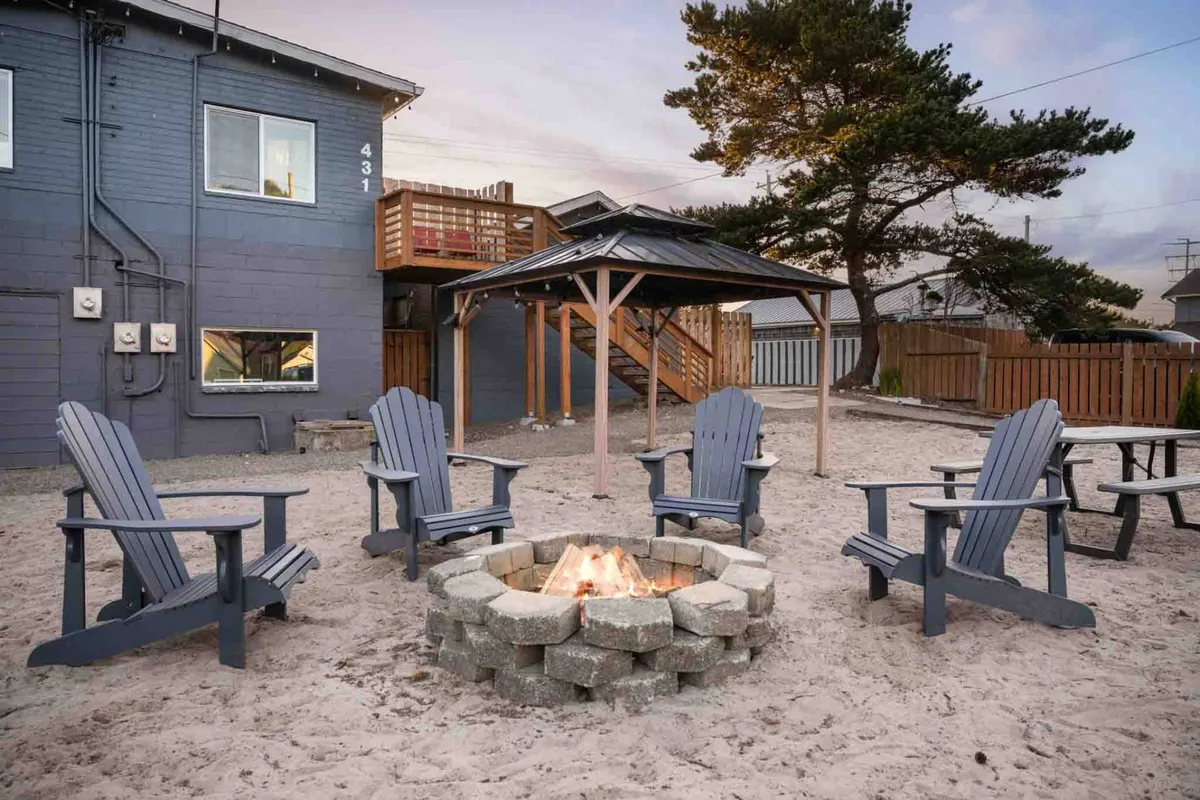 An inviting exterior scene featuring a semi-private gazebo and fire pit surrounded by Adirondack chairs. The cozy setting offers a place for guests to gather, share stories, or enjoy a quiet moment under the stars, all within the property grounds.