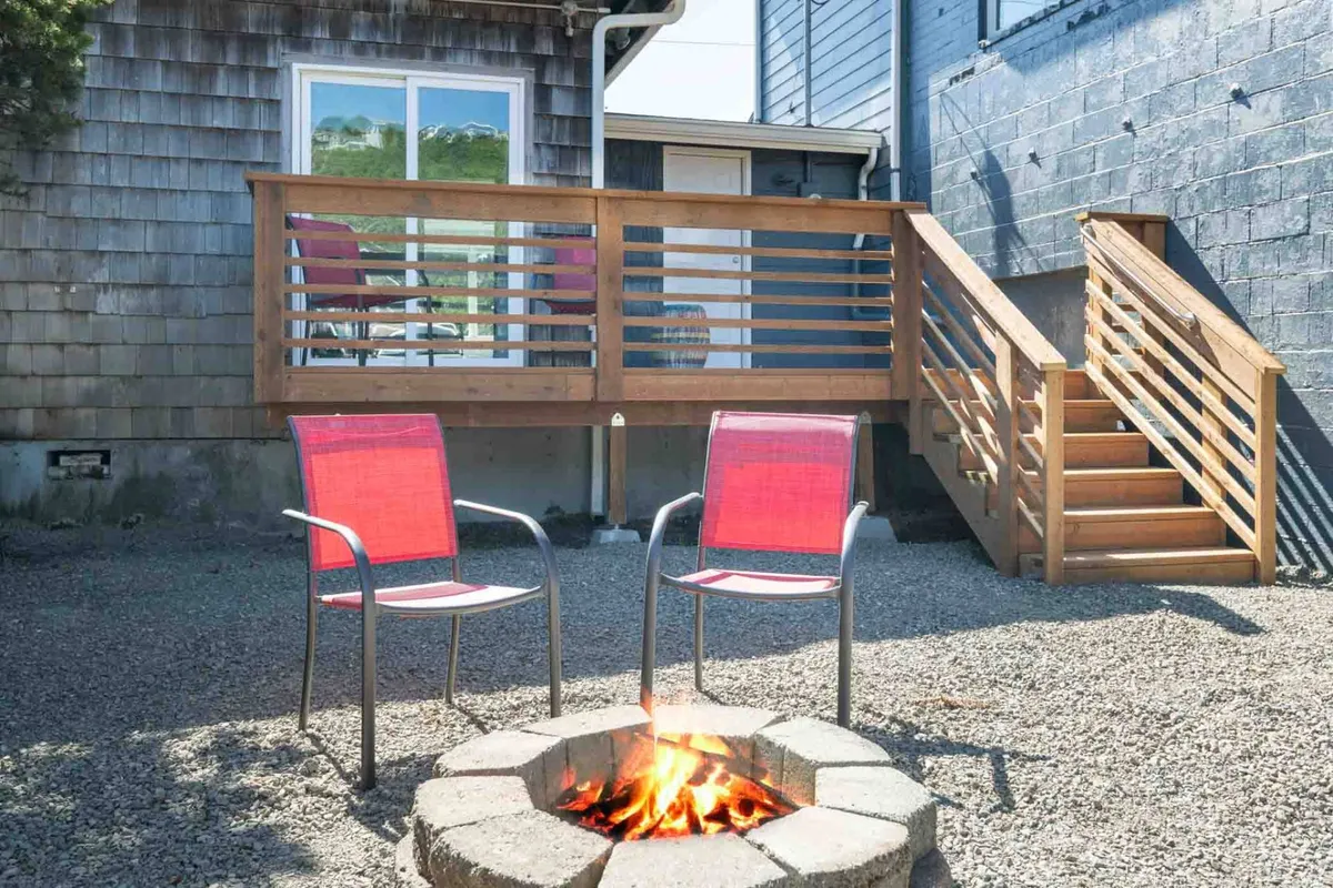 An exterior shot featuring a wooden deck with chairs arranged around a fire pit, inviting guests to gather, relax, and socialize outdoors. The cozy setting is ideal for unwinding after a day of exploring with your pet.
